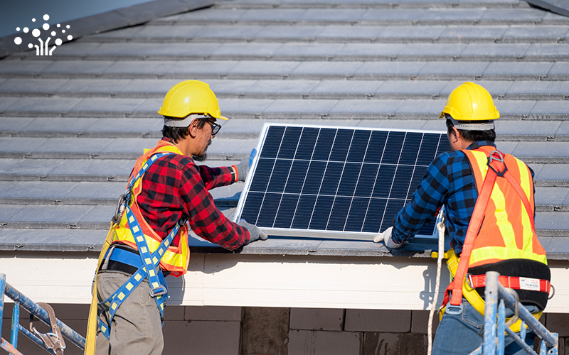 Two technicians installing a solar panel on a rooftop for a landed home.