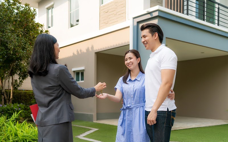 Asian couple receiving keys to a house with solar panels Asian couple receiving keys to a house with solar panels
