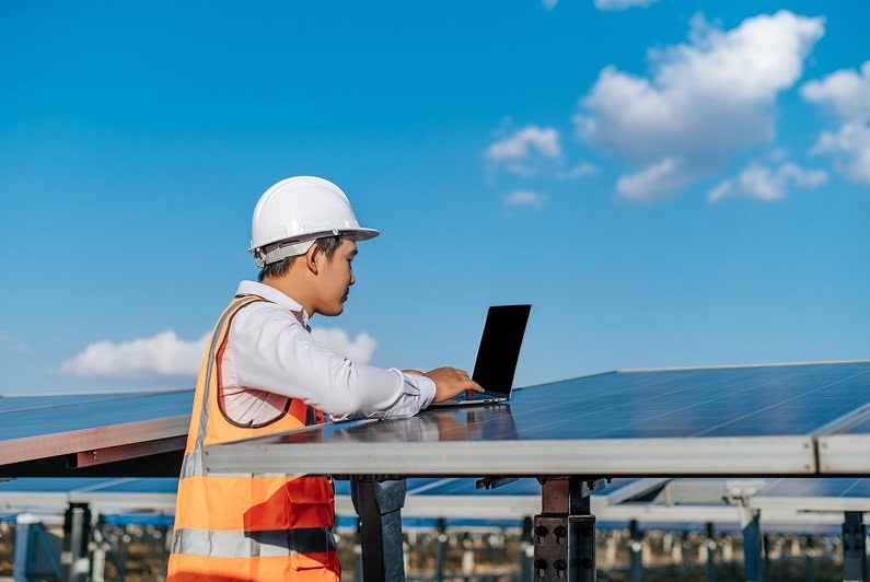 Engineer conducting solar panel safety assessment using laptop outdoors.