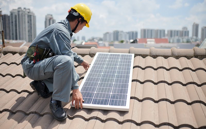 Solar installer positioning panel on residential tiled roof
