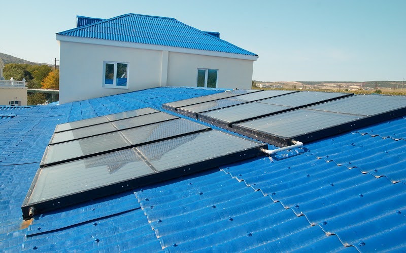 Solar panels installed on blue metal roof absorbing sunlight.
