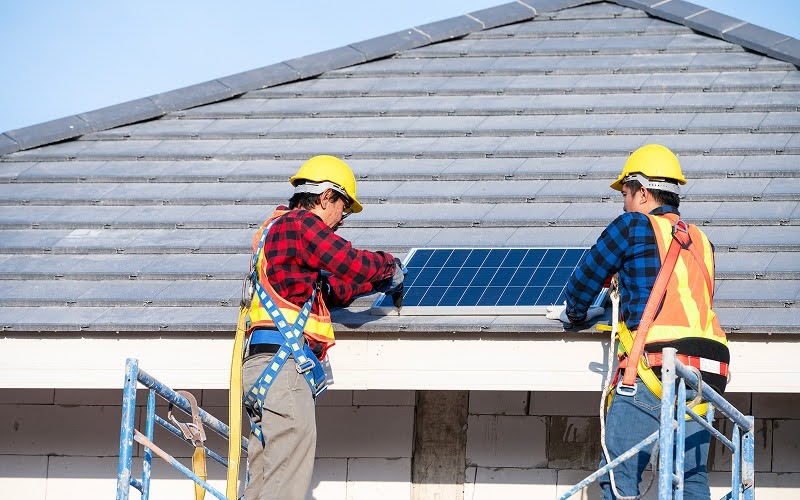 Workers installing solar panel on roof during home renovation